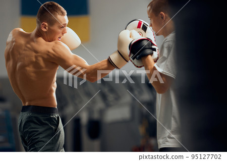 Two sportive men, professional boxer and personal trainer is practicing boxing at gym. Sport, strength, energy and power 95127702