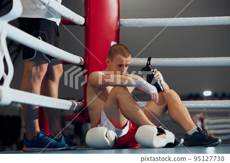 Pre-fight consultation. Young boxer training with personal coach, trainer at boxing ring at sports gym. Sport, strategy, studying, skills and achievements Pre-fight consultation. Young boxer training with personal coach, trainer at boxing ring at sports gym. Sport, strategy, studying, skills and achievements 95127738