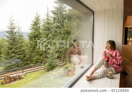 Woman rests in house with scenic view on mountains Woman rests in house with scenic view on mountains 95128980