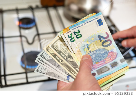 Payment of utilities. Euro and dollar bills lie near a burning gas burner. The concept of increasing the cost of natural gas supply and payment. Energy crisis. High cost, the price of gas. 95129358