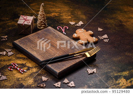 Beautiful gingerbread on a brown ceramic plate with Christmas tree decorations Beautiful gingerbread on a brown ceramic plate with Christmas tree decorations 95129480