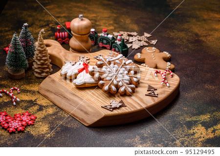 Beautiful gingerbread on a brown ceramic plate with Christmas tree decorations 95129495