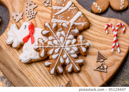Beautiful gingerbread on a brown ceramic plate with Christmas tree decorations 95129497