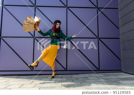 A happy shopaholic girl throws her bags near a shopping center. Have fun shopping on Black Friday. the girl in the store is happy with her purchases, throws packages. Consumer concept. A happy shopaholic girl throws her bags near a shopping center. Have fun shopping on Black Friday. the girl in the store is happy with her purchases, throws packages. Consumer concept. 95129565