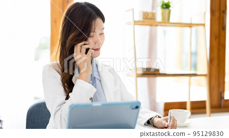 Finance workers are reviewing the company's financial data on a laptop and using smartphones to communicate or chat with the team during  social distances, Talk on the phone or video call. 95129830