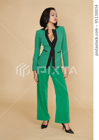 Asian fashion model demonstrating green elegant suit against beige background Asian fashion model demonstrating green elegant suit against beige background 95130034