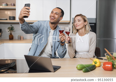 Cute multinational couple taking selfie or having video conversation with friends Cute multinational couple taking selfie or having video conversation with friends 95130055