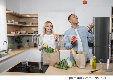 Arab guy throwing tomatoes for fun in kitchen. Arab guy throwing tomatoes for fun in kitchen. 95130199