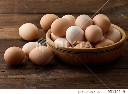 Fresh brown chicken eggs in a round wooden plate on the table 95130249
