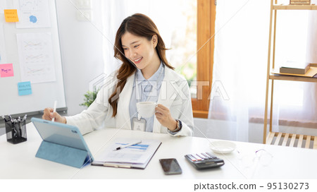 Businesswoman using laptop to work, Asian woman working in the office, Financial clerk or accountant with documents and equipment working on the desk, Using tablet for financial transactions. Businesswoman using laptop to work, Asian woman working in the office, Financial clerk or accountant with documents and equipment working on the desk, Using tablet for financial transactions. 95130273