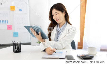 Businesswoman using laptop to work, Asian woman working in the office, Financial clerk or accountant with documents and equipment working on the desk, Using tablet for financial transactions. 95130304