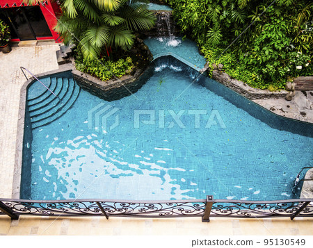 Stunning aerial view of a swimming pool with tropical trees all around 95130549