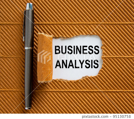 The text 'business analysis' appearing behind torn brown paper. Beautiful metalic pen. The text 'business analysis' appearing behind torn brown paper. Beautiful metalic pen. 95130758