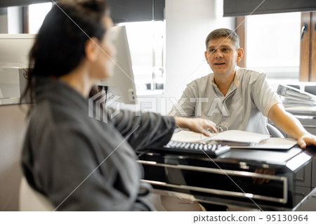 Woman in a bathrobe on appointment with senior therapist 95130964