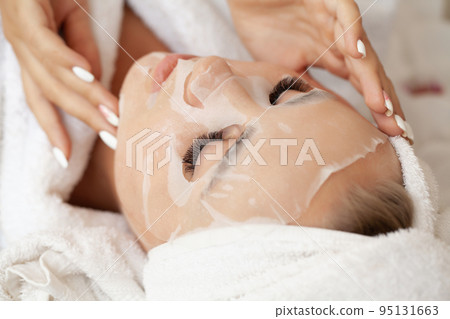 Young woman with cloth mask at spa salon 95131663
