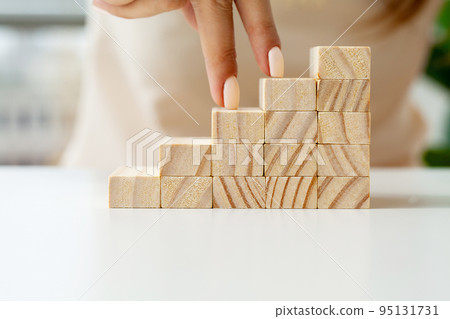 Close up Woman hand arranging wood block stacking as step stair. Close up Woman hand arranging wood block stacking as step stair. 95131731