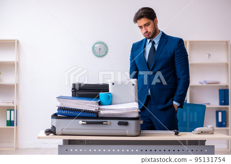 Young male employee preparing for business trip at workplace Young male employee preparing for business trip at workplace 95131754