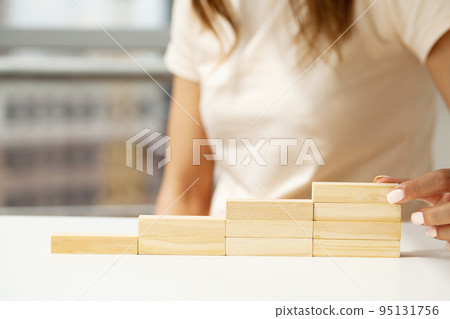 Close up Woman hand arranging wood block stacking as step stair. Close up Woman hand arranging wood block stacking as step stair. 95131756