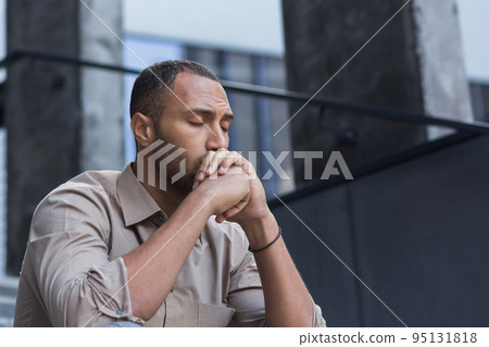 Close-up photo portrait of upset office worker fired businessman in depression, man with closed eyes sitting on stairs of office building outside. Close-up photo portrait of upset office worker fired businessman in depression, man with closed eyes sitting on stairs of office building outside. 95131818