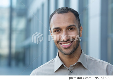 Close up photo portrait of young African American student, man smiling and looking at camera, businessman outside office building wearing shirt. Close up photo portrait of young African American student, man smiling and looking at camera, businessman outside office building wearing shirt. 95131820