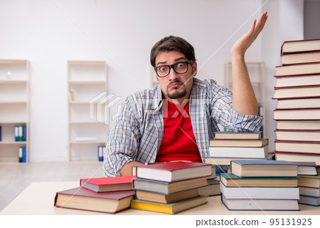 Young male student and too many books in the classroom Young male student and too many books in the classroom 95131925