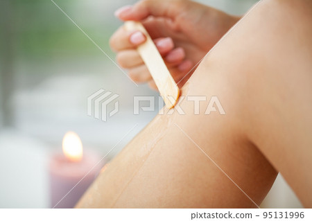 Depilation procedure with wax strip on the legs Depilation procedure with wax strip on the legs 95131996