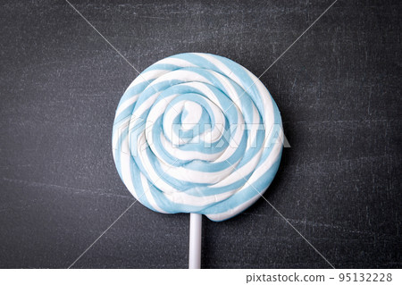 Blue candy on a stick, lollipop. Dark chalkboard background Blue candy on a stick, lollipop. Dark chalkboard background 95132228