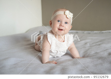 Portrait of a beautiful little baby girl lying on her stomach and looks away with admiration. Portrait of a beautiful little baby girl lying on her stomach and looks away with admiration. 95132679
