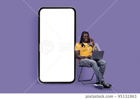 Happy handsome black guy working on purple, having phone call Happy handsome black guy working on purple, having phone call 95132863