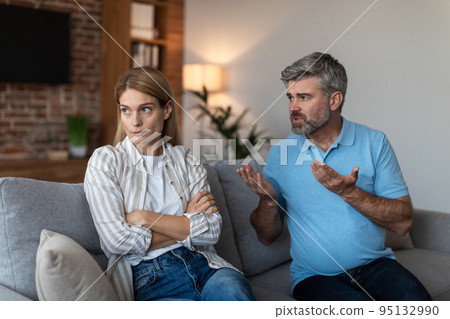 Sad offended middle aged european female ignores arguments of male during quarrel in living room interior 95132990