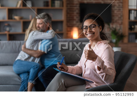 Smiling black young doctor in glasses show thumb up approves therapy of mature european couple 95132993