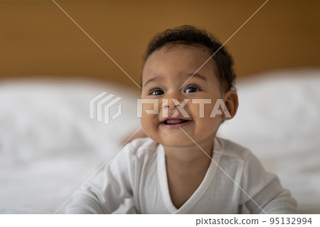 Adorable Cute Infant African American Baby Relaxing On Bed, Lying On His Tummy Adorable Cute Infant African American Baby Relaxing On Bed, Lying On His Tummy 95132994