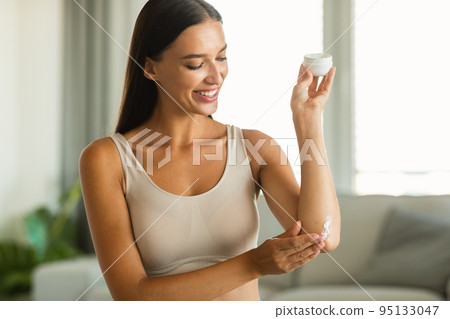 Happy Woman Applying Moisturizer Jar Enjoying Skincare At Home 95133047