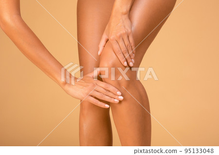 Trauma, stretching. Cropped shot of young woman touching and massaging her sore injured knee, closeup 95133048