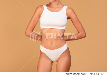 Cropped shot of fit sporty lady in white underwear showing perfect fit figure standing with hands behind back 95133168