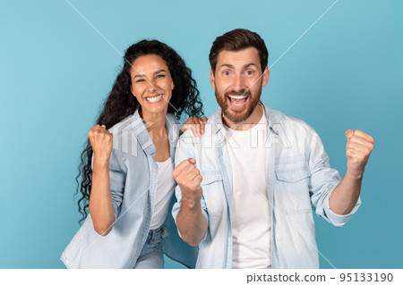 Portrait of satisfied young arab lady and european male with beard looking at camera, show victory 95133190
