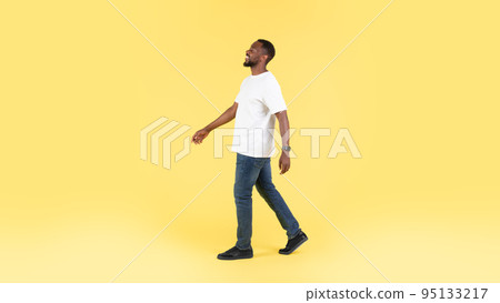 Carefree African American Man Walking Smiling Looking Aside, Yellow Background 95133217