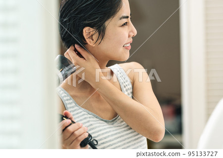一個女人洗完澡後用吹風機吹乾頭髮 95133727