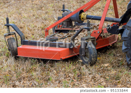 Tractor trimming and removing small branches on the ground in autumn Tractor trimming and removing small branches on the ground in autumn 95133844
