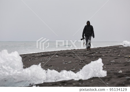 Photographer picking up pieces of icebergs Photographer picking up pieces of icebergs 95134129