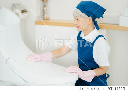 Housekeeper senior woman cleaning the toilet Housekeeper senior woman cleaning the toilet 95134525