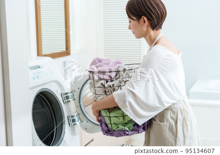 A woman using a drum-type washing machine A woman using a drum-type washing machine 95134607