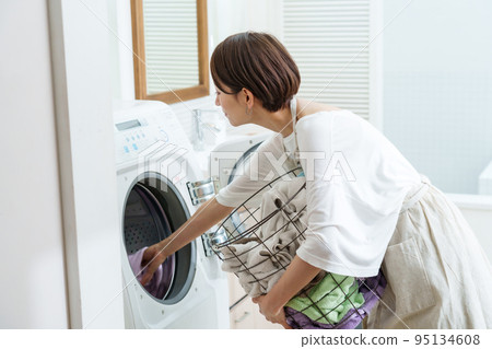 使用滾筒式洗衣機的婦女 使用滾筒式洗衣機的婦女 95134608