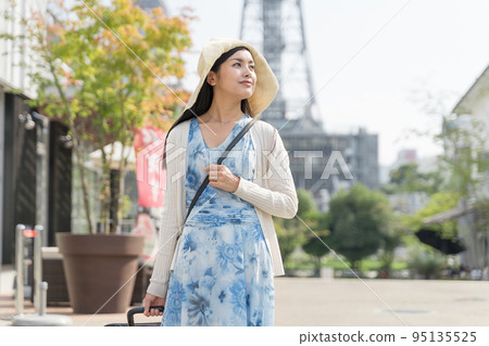 A young woman pulling a suitcase and sightseeing in Nagoya 95135525