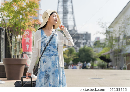 A young woman pulling a suitcase and sightseeing in Nagoya 95135533
