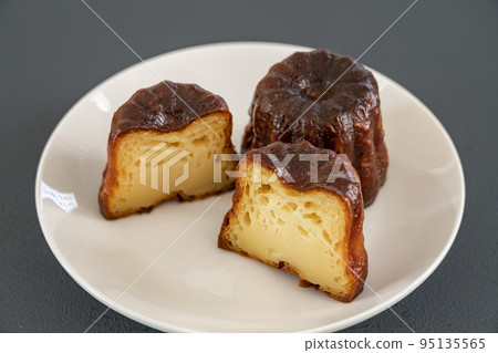 French pastry canelé on a white plate [black background] 95135565