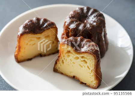 French pastry canelé on a white plate [black background] 95135566