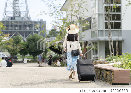 Back view of a young woman pulling a suitcase and sightseeing in Nagoya 95136553