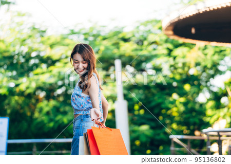 Young adult asian woman holding shopping bags at outdoor on day 95136802