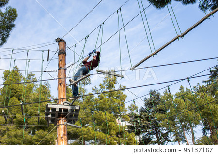 A man is resting in a rope amusement park. Front view. 95137187